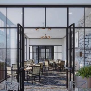 A modern restaurant interior featuring glass walls, ample natural light, and neatly arranged tables and chairs.