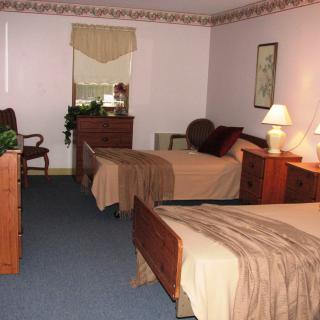 A cozy bedroom with two beds and classic wooden furniture.