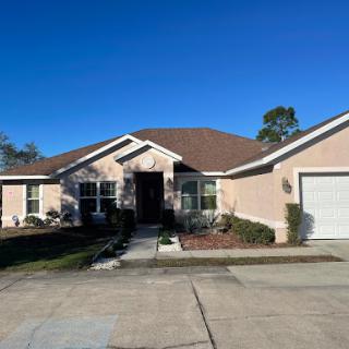 A charming single-story house with a well-maintained front yard and clear blue skies.