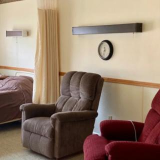 A cozy living space with recliners, a bed, and a wall-mounted clock.