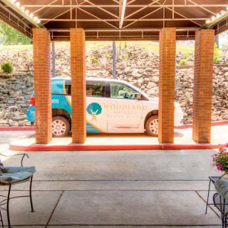 A small car parked under a covered area with brick columns.