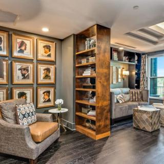 A stylish and cozy living room featuring a bookshelf, framed artwork, and comfortable seating.