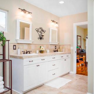 A well-lit bathroom features a double-sink vanity with neutral tones and decorative accents.