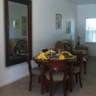 A cozy dining area with a round table set for dinner and a large mirror reflecting the room.