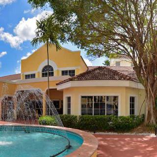 A yellow house with a pool and fountain in front, surrounded by trees.