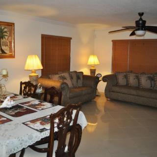 A cozy living room and dining area featuring sofas, a dining table, and ambient lighting from lamps.