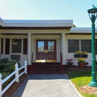 A welcoming entrance to a charming building with landscaped surroundings and decorative outdoor lighting.