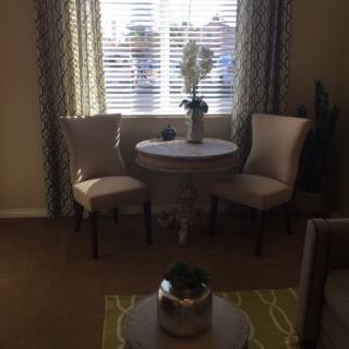 A cozy living room corner with a small round table and two chairs by the window.