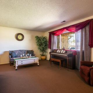 A cozy living room featuring a sofa, coffee table, and piano near a window with curtains.
