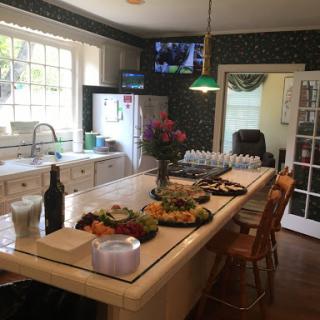 A cozy kitchen setup featuring a dining table with an array of fruits and flowers, perfect for gatherings.