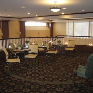 A cozy lounge area featuring various chairs and tables, illuminated by overhead lighting.
