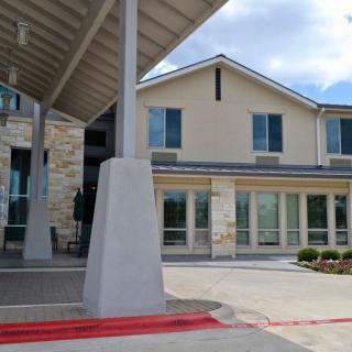 A modern building entrance with a covered driveway and large windows.
