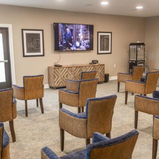 A cozy home theater setup with rows of comfortable chairs facing a large screen.
