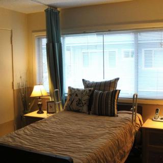 A cozy bedroom with a neatly made bed, decorative pillows, and soft lighting from bedside lamps near the window.