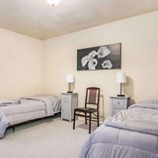 A minimalist bedroom featuring two single beds, a central chair, and wall-mounted artwork.