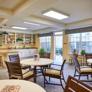 A bright and welcoming dining area with tables, chairs, and large windows.