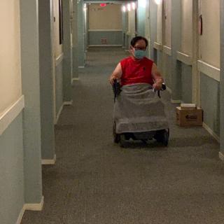 A person in a wheelchair navigating through a hallway.