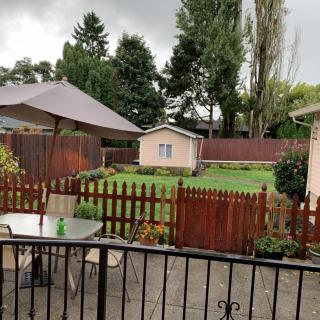 A cozy backyard with a patio set, umbrella, and fenced garden area on a cloudy day.