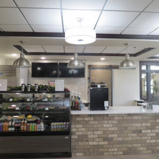 A modern cafe counter with a display case and overhead lighting.