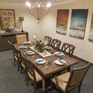 A beautifully arranged dining room featuring a wooden table set for a meal, complemented by modern decor and artwork.