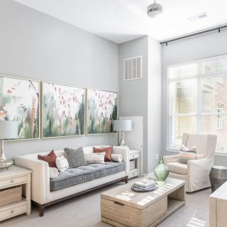 A modern living room with neutral tones, featuring elegant artwork and abundant natural light.