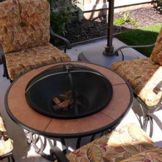 Outdoor patio setup with a fire pit and cushioned chairs.