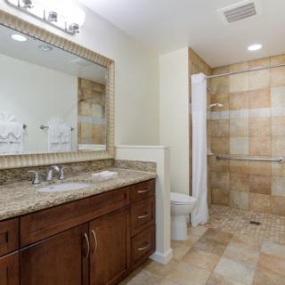 A modern bathroom featuring a stylish vanity, spacious mirror, and a tiled shower area.