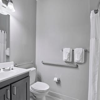 A clean and modern bathroom featuring a toilet, sink, mirror, and towel rack.