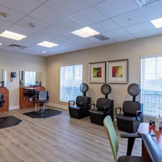 A tidy hair salon featuring styling chairs and hair drying stations.