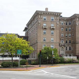 A historic urban building with trees lining the street corner.