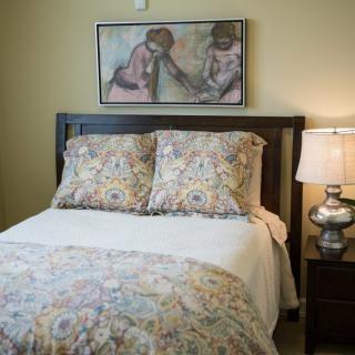 A cozy bedroom with patterned bedding and a stylish lamp beside the bed.