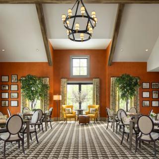 A spacious lounge area with stylish furniture, a central chandelier, and decorative plants.
