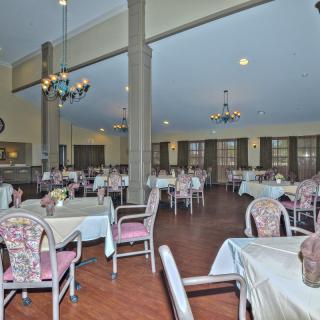 A spacious dining area with neatly arranged tables and chairs under elegant chandeliers.