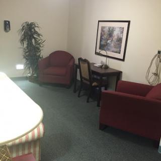 A cozy waiting area featuring two chairs, a small table, and a decorative plant.
