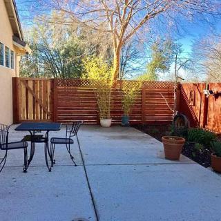 A serene patio with outdoor furniture and potted plants under a clear blue sky.