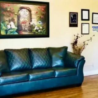 A cozy living room featuring a green sofa, artwork on the wall, and decorative elements.