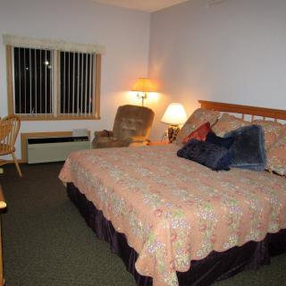A cozy hotel bedroom with a large bed, soft lighting, and comfortable seating.