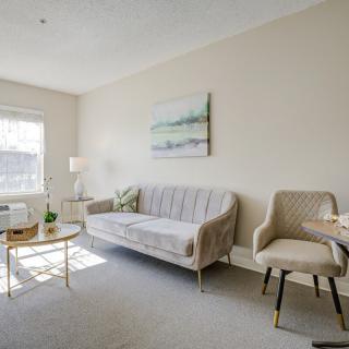 A bright and cozy living room with a sofa, chairs, coffee table, and artwork on the wall.
