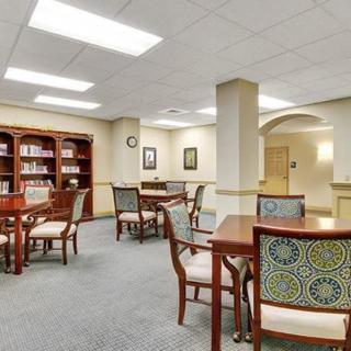 A well-lit library space with tables, chairs, and bookshelves.