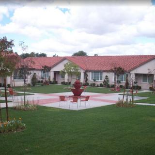 A scenic courtyard with a central fountain and surrounding buildings, featuring well-maintained lawns and gardens.