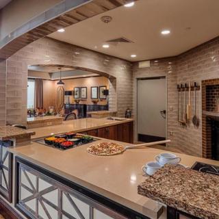 A modern kitchen interior featuring a countertop with a pizza, wood accents, and warm lighting.