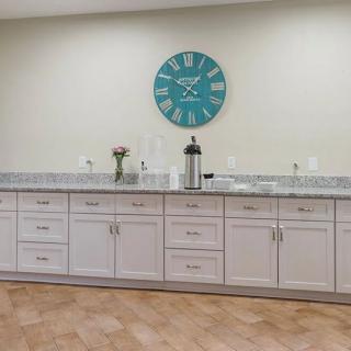 A modern kitchen with sleek cabinets and a large wall clock.