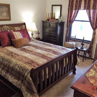 A cozy traditional bedroom with a wooden bed, dresser, and decorative pillows.