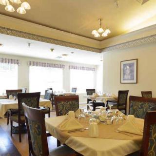 An empty restaurant dining room with elegantly set tables and comfortable seating.