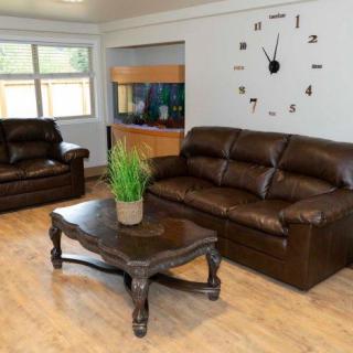 A cozy living room with leather sofas, a coffee table, and a large wall clock.