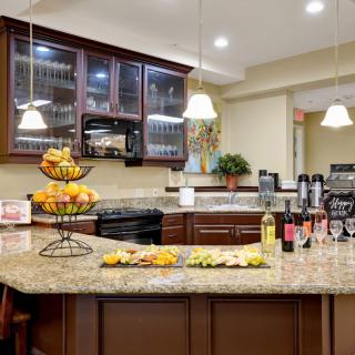 A modern kitchen with a granite countertop featuring an assortment of fruits and snacks.
