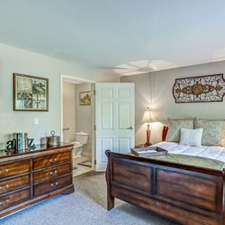 A cozy bedroom with a wooden bed, matching dresser, and tasteful decorations.