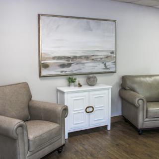 A cozy and modern living room setup featuring neutral-toned furniture and a serene artwork.