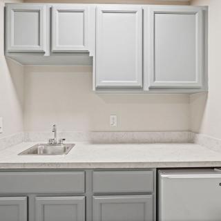 A compact kitchen with light gray cabinets and a small sink.