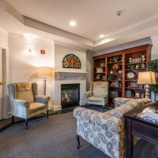 A cozy living room with a fireplace and comfortable seating, featuring elegant decor and a well-stocked bookshelf.